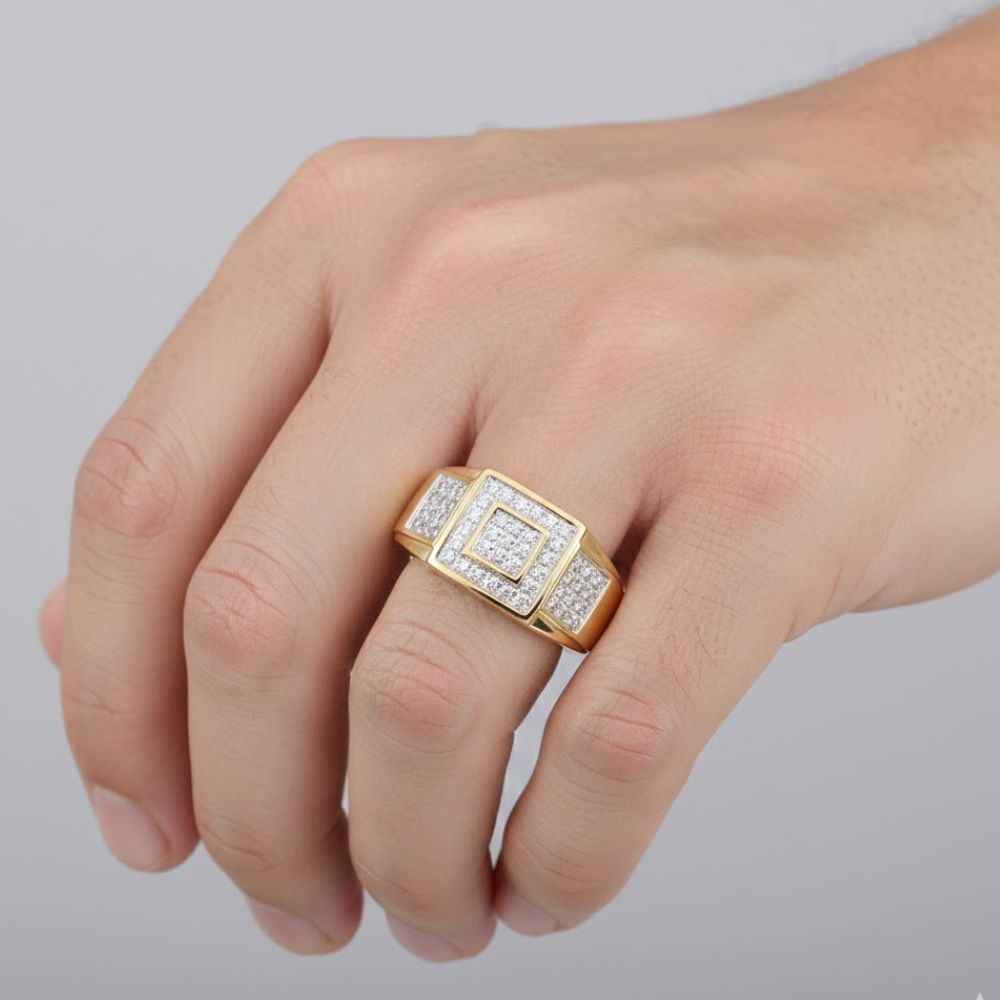 A close-up of a hand wearing the 10K Yellow Gold Diamond Square Ring 1/4CT, showcasing its bold square design set with sparkling diamonds, set against a plain light gray background.