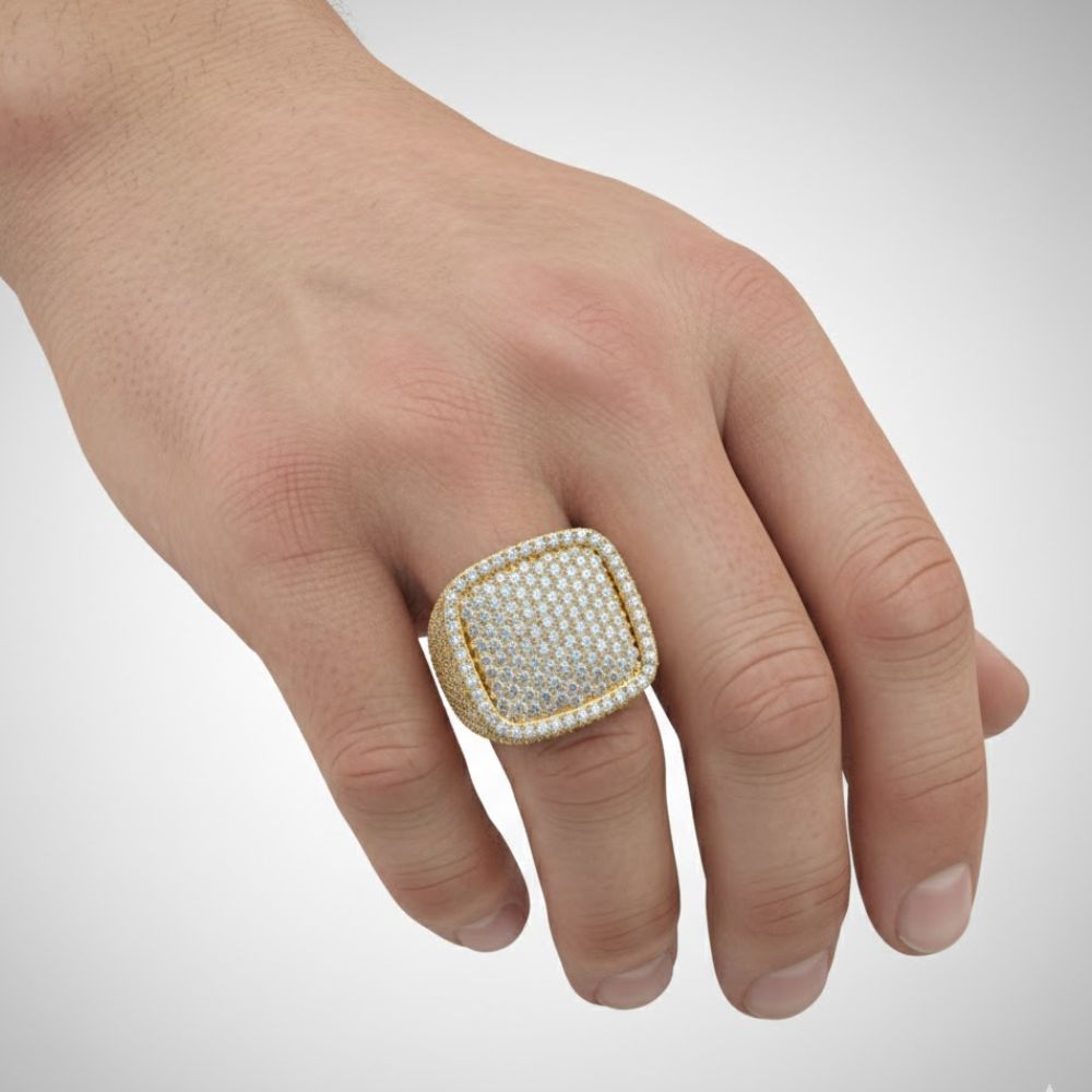 A hand wears the Iced Cushion Diamond Ring – 6.48 CT Pavé Design, a large square-shaped men's gold ring encrusted with sparkling pavé diamonds, shown on the ring finger against a plain light background.