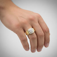 A hand wears the 1/4CTW Natural Diamond Men’s Ring in 10k gold, featuring a square face with natural diamonds, displayed against a plain light gray background.