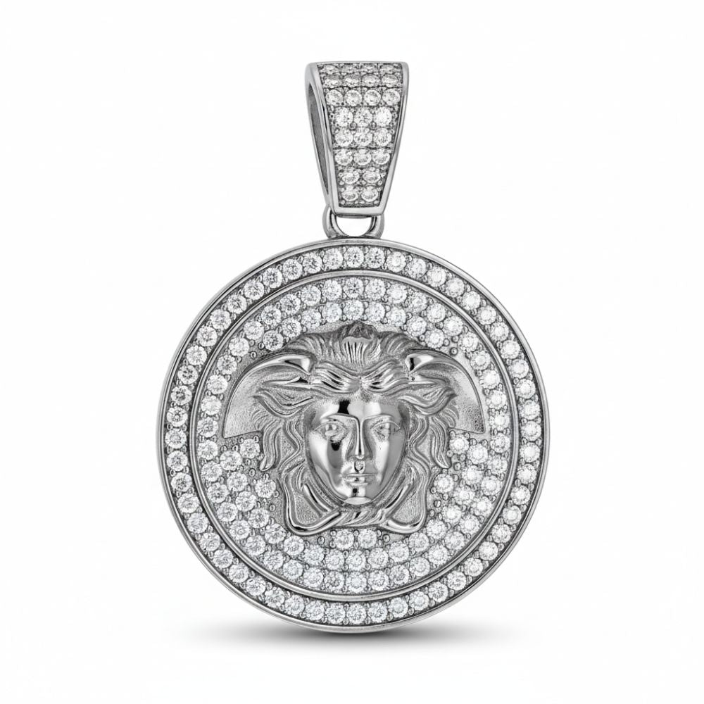 The Moissanite Medusa Egyptian Charm Pendant features a round sterling silver design with a raised classical face and flowing hair, accented by sparkling moissanite stones on both the pendant and bail for added brilliance.