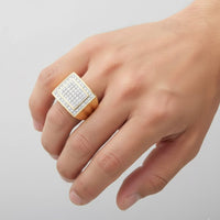 A hand displays the 10k Yellow Gold Diamond Square Ring 1/2 CT, featuring multiple rows of sparkling white diamonds in a square design, set in 10k yellow gold against a plain light background.