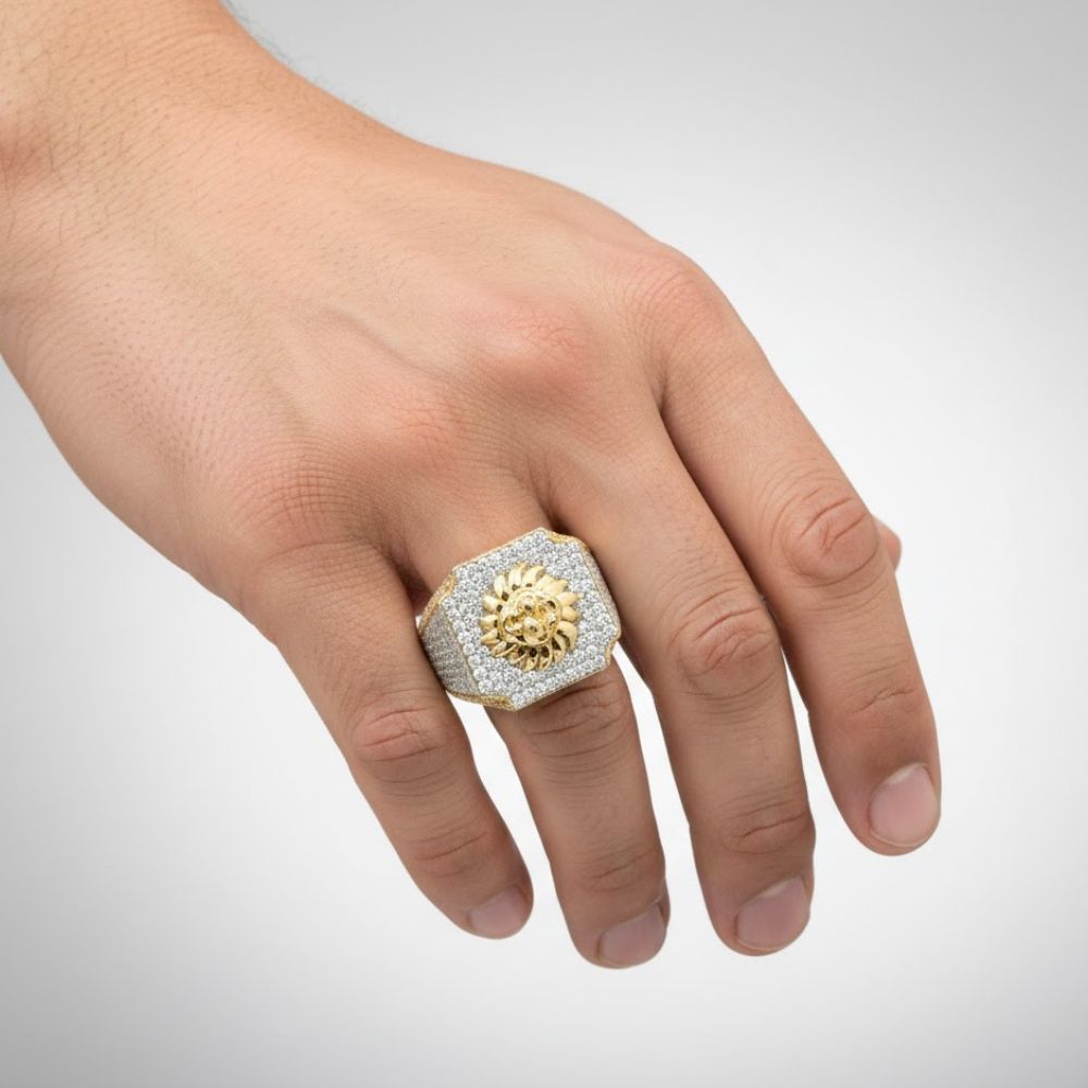 A hand displays the 2.43 CTW Cluster Lion Diamond Ring – 14k Gold, featuring a gold lion head centerpiece encrusted with sparkling diamonds, set against a plain light background—a bold statement ring for men.