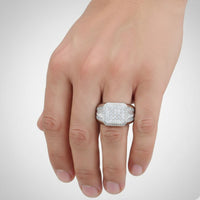 A hand showcases the Square Head Fashion Moissanite Ring—a striking sterling silver piece with multiple sparkling stones—set against a plain white background, highlighting its modern elegance.