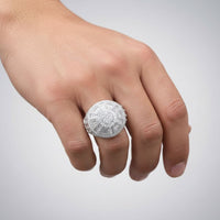 A hand displays the Mens Round Baguette Moissanite Round Cluster Fashion Ring, featuring a large cluster of sparkling stones on a sterling silver band, set against a light gray background.