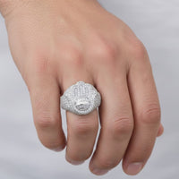 A close-up of a hand wearing the Baguette Moissanite Hamsa Symbol Religious Ring, featuring a large Hamsa design adorned with sparkling moissanite stones, set against a blurred white background.