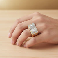 A hand displays the 0.73 CTW Natural Diamond Cluster Ring in 14k yellow gold, set with natural diamonds, on a light wooden surface against a blurred golden background.