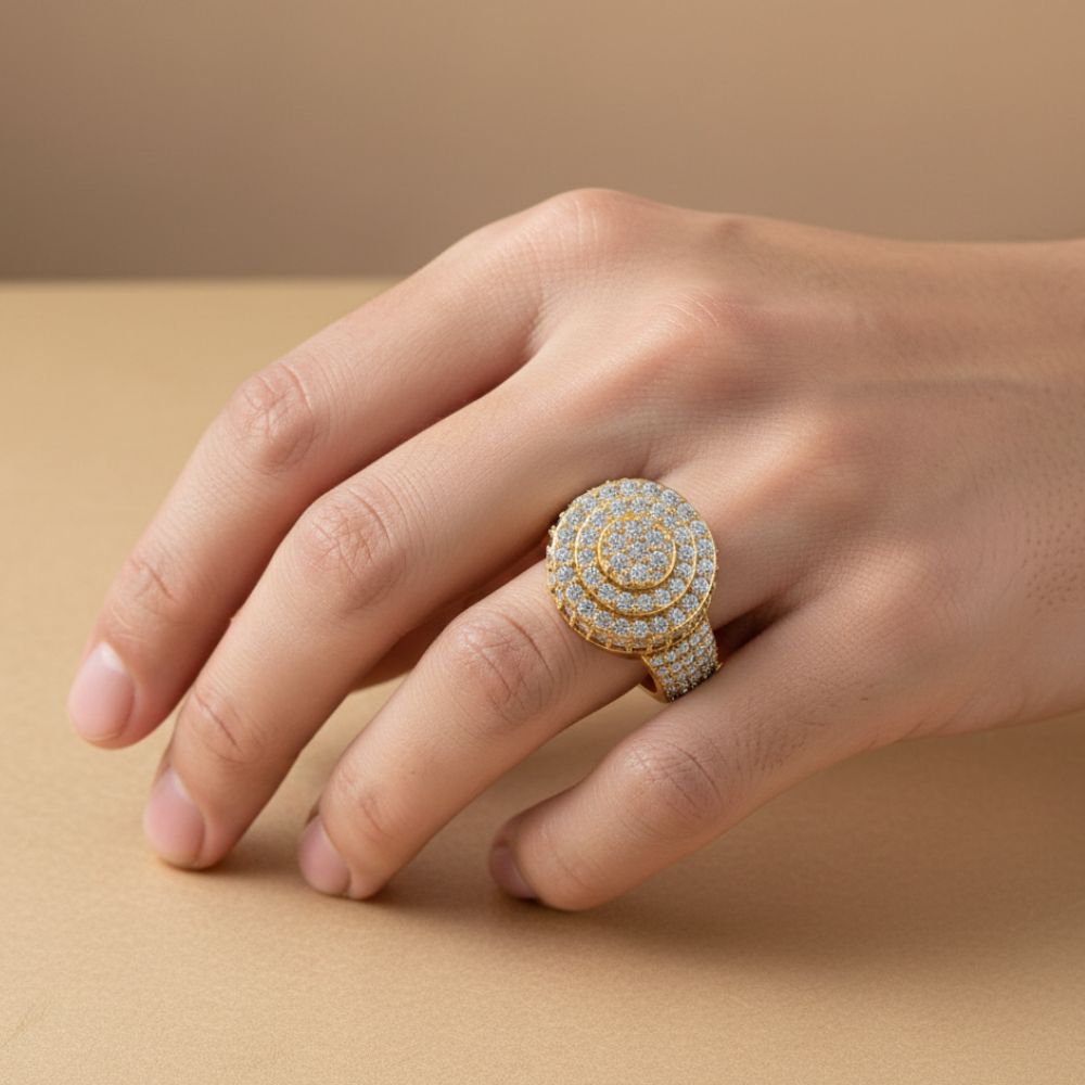A hand rests on a beige surface, showcasing the Layered Round Diamond Ring – 2.33 CT Gold Design, a bold men's gold ring featuring multiple rows of sparkling white diamonds arranged in concentric circles.