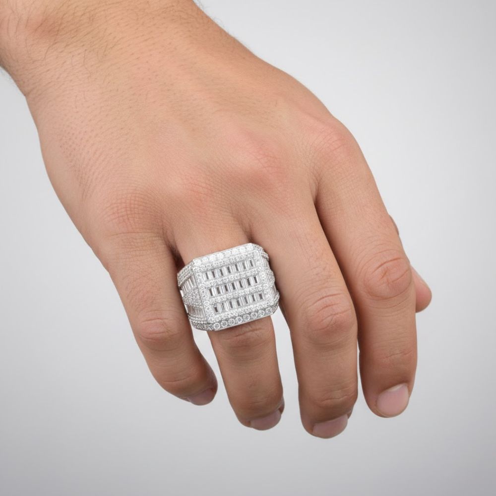 A hand wears the Baguette Moissanite Square Head Fashion Ring with baguette-cut stones and diamonds on the middle finger, set against a plain light background.