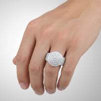 A hand showcases the Mens Moissanite Round Head Cluster Fashion Ring, a sterling silver piece featuring multiple sparkling moissanite stones, set against a plain light background.