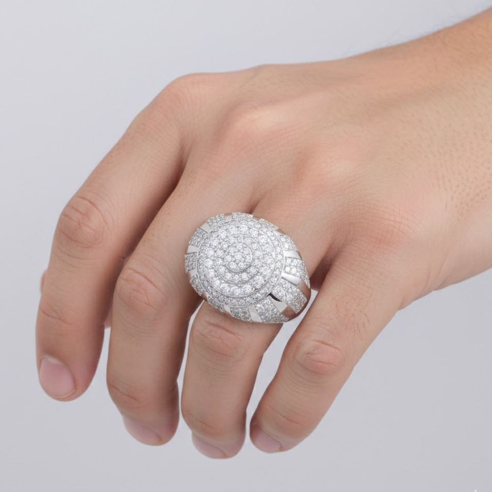 A hand displays the Moissanite Round Silver Fashion Ring, featuring multiple rows of sparkling stones on a large round sterling silver band. A plain, light background enhances the brilliance of its design.