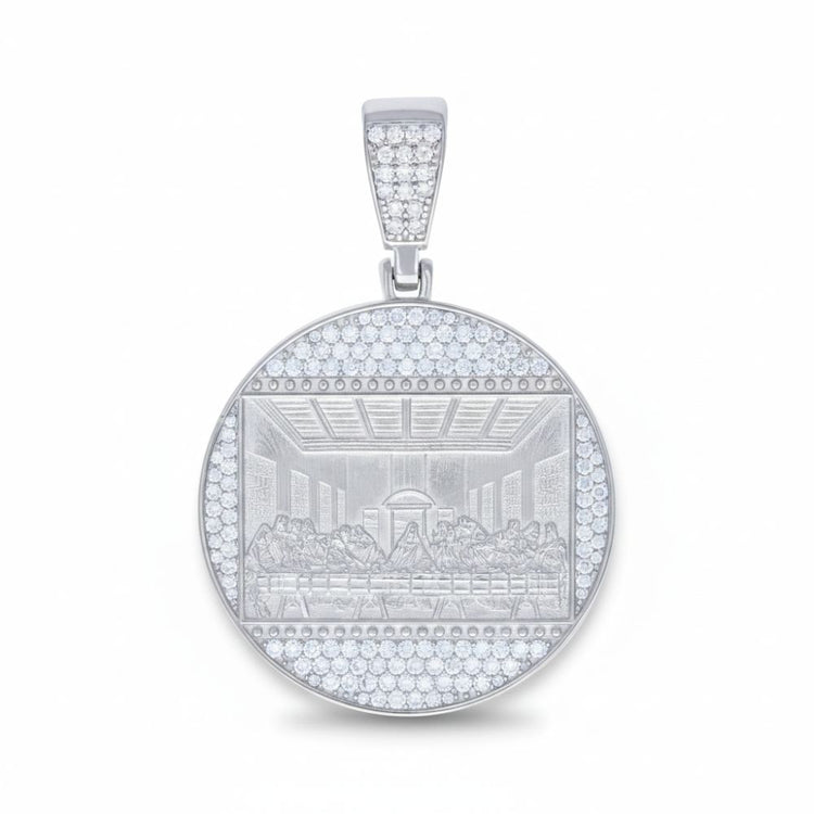 The Moissanite Last Supper Religious Charm Pendant features a round sterling silver design with an engraved depiction of the scene, surrounded by sparkling moissanite gemstones along the border and bail.
