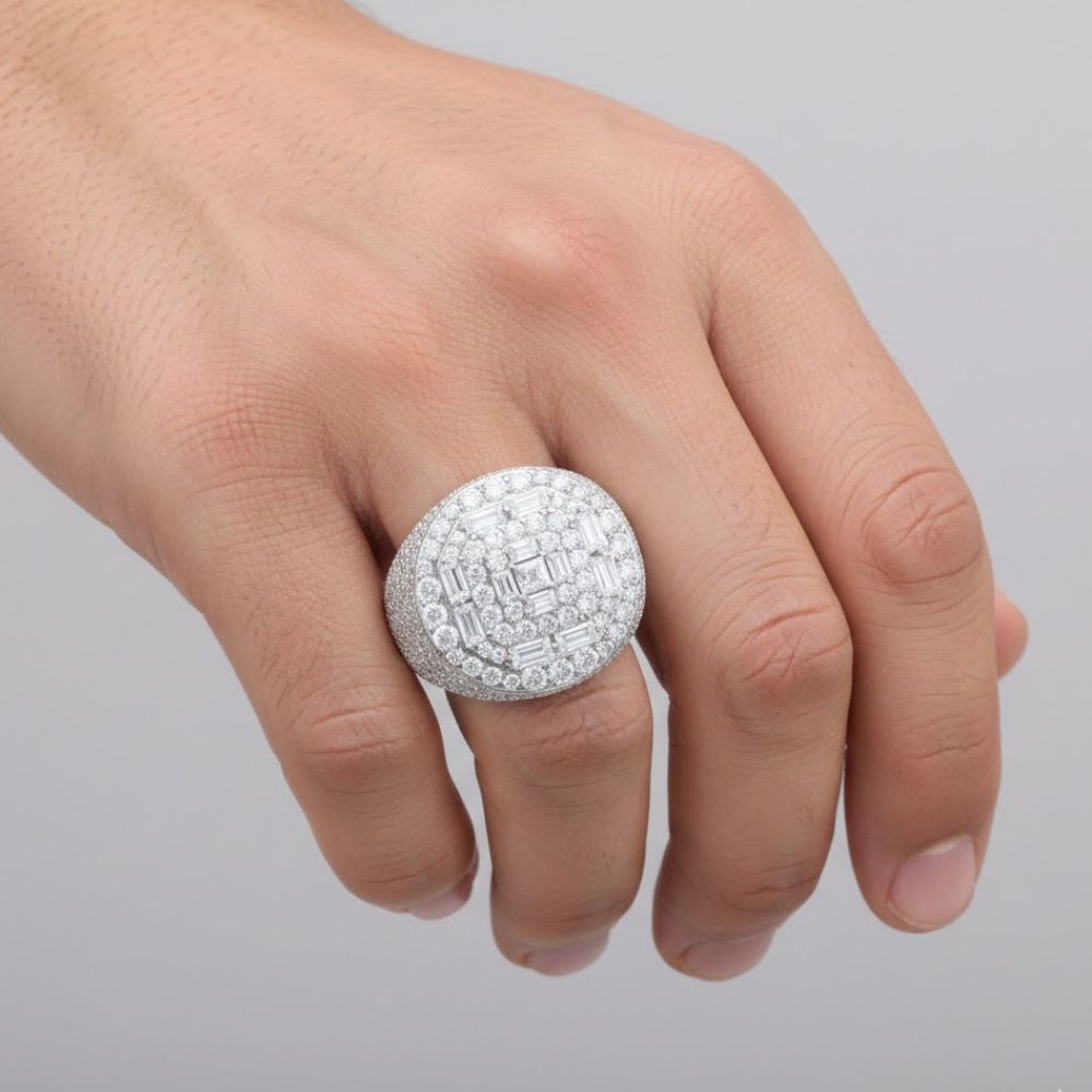 A hand showcases the Silver Moissanite Baguette Round Ring, featuring sparkling stones set in sterling silver, against a plain gray background.