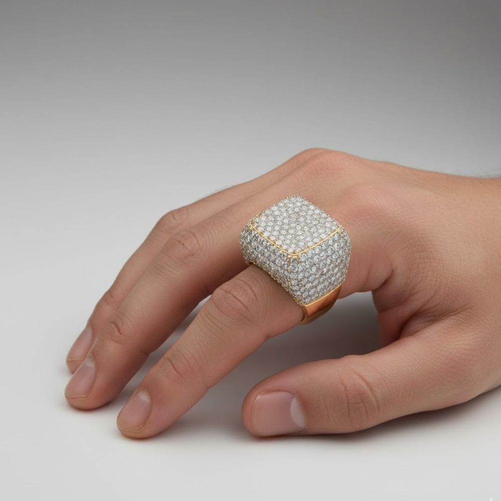 A hand displays the Iced-Out Square Cluster Ring, featuring 13.1 CT lab diamonds set in 14K gold; its bold, square design covers most of the finger against a plain light gray background.