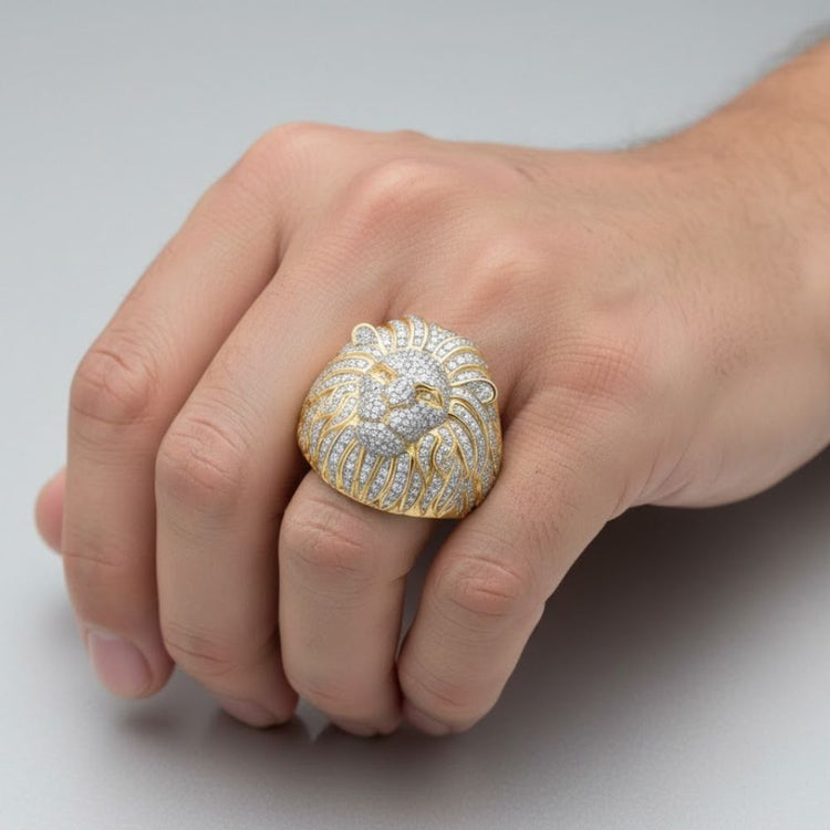 A close-up of a hand wearing the 1 3/4CTW Lion Face Diamond Men’s Ring in 10k yellow gold, featuring a bold lion design encrusted with natural diamonds, set against a plain light gray background.
