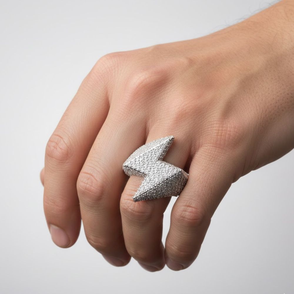 A hand wears the Lightning Strike Diamond Ring – 4.40 CT Pavé Design, a striking men’s statement piece shaped like a lightning bolt and encrusted with sparkling lab-grown diamonds, set against a simple light backdrop.