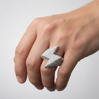 A hand wears the Lightning Strike Diamond Ring – 4.40 CT Pavé Design, a striking men’s statement piece shaped like a lightning bolt and encrusted with sparkling lab-grown diamonds, set against a simple light backdrop.