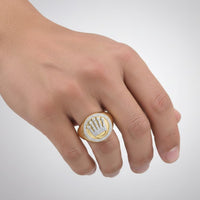 A hand wears the 3/8CT Diamond Crown Men’s Ring in 14K yellow gold, featuring a diamond-studded circular face and crown-like design, displayed against a plain light background.