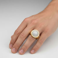 A close-up of a hand wearing the 0.49 CTW Cluster Round Natural Diamond Ring in 14K yellow gold, featuring a textured, silver-toned circular center with natural diamonds, against a plain light background.