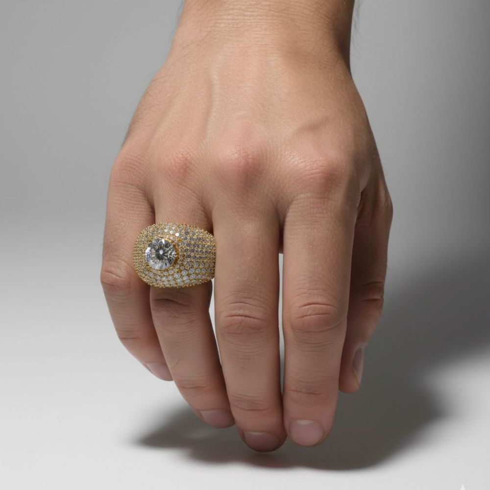 A hand displays the Domed Solitaire Diamond Ring – 15.21 CT Gold Design, a men’s gold ring with small lab-grown diamonds and a prominent round center stone, set against a plain light background.