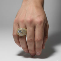 A hand displays the Domed Solitaire Diamond Ring – 15.21 CT Gold Design, a men’s gold ring with small lab-grown diamonds and a prominent round center stone, set against a plain light background.
