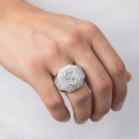 A hand with light skin tone wears the Moissanite Octagon Head Dollar Sign Currency Ring—a large, octagonal sterling silver piece adorned with sparkling stones—on the ring finger, set against a plain white background.