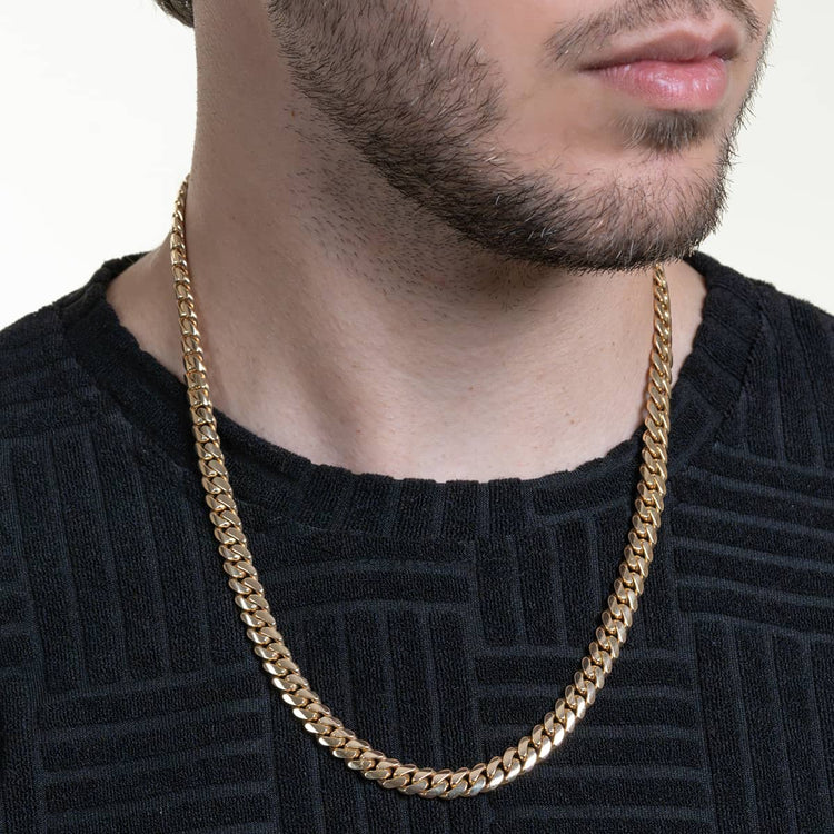 A man in a textured black shirt wears the Handmade Miami Cuban Link Chain—Solid Gold, Ready to Ship. Shot from shoulders up, only his lower face is visible, highlighting the bold 14k yellow gold chain.