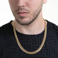 A man wearing a black textured shirt and the Cuban Link Chain - Ready to Ship Solid Gold, shown from the shoulders up against a plain white background.