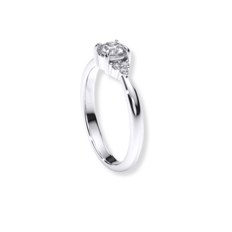 The Round Brilliant Cut Diamond Engagement Ring features a silver band with a round brilliant center diamond and two smaller side diamonds, shown on a white background.