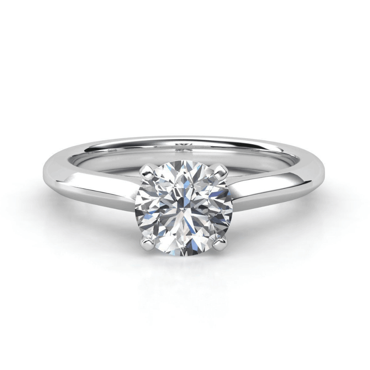 The Classic Round Solitaire Lab Grown Diamond Engagement Ring features a round brilliant-cut diamond in a polished white metal band with four prongs for timeless elegance.