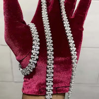 A hand in a red velvet glove showcases sparkling moissanite jewelry, including the Silver Cross Moissanite Necklace, against a neutral background.