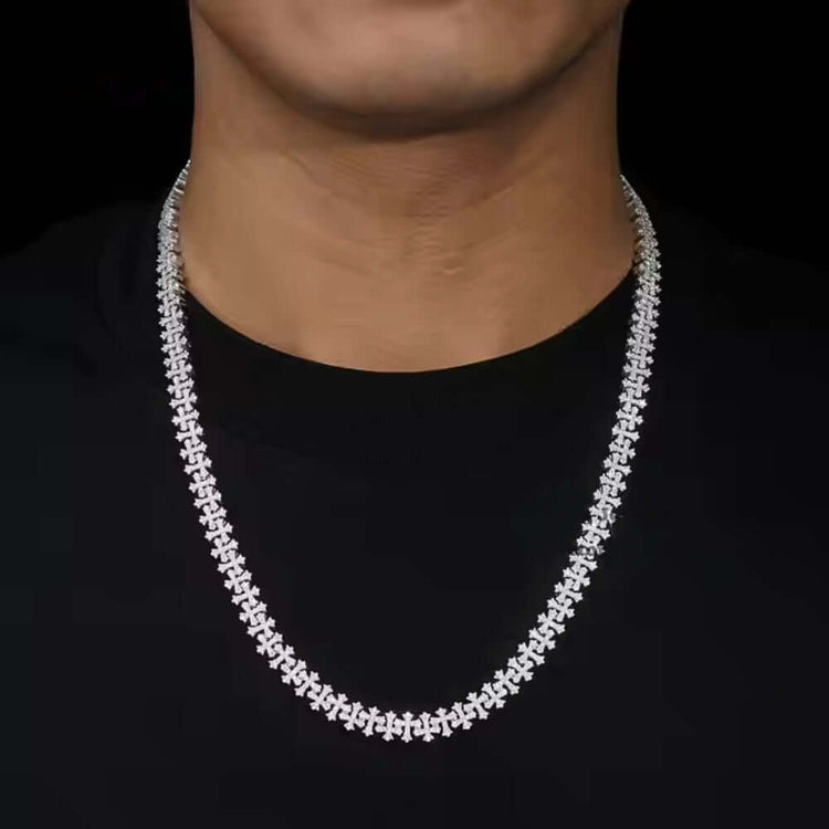 A person wears the Silver Cross Moissanite Necklace, featuring a sparkling cross design, shown against a black shirt and black background.