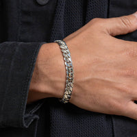 A close-up of a wrist wearing the Silver Cuban Link Bracelet - 10mm, its bold, gleaming links standing out against a black textured jacket.
