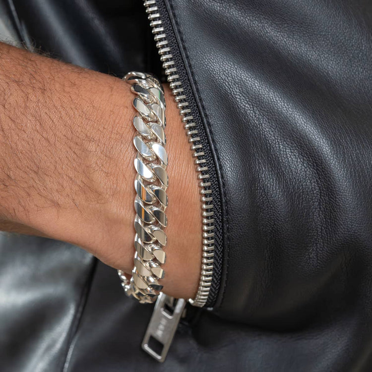 A close-up of a person wearing the 12mm Handmade Miami Cuban Link Bracelet in 950 silver, styled with a black leather jacket and visible zipper.