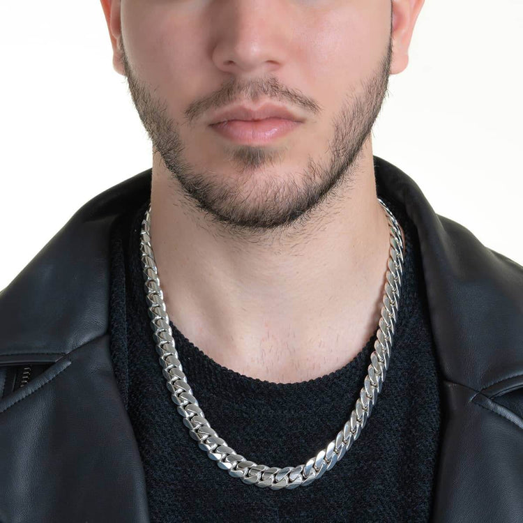 A close-up of a man wearing the 12mm Handmade Miami Cuban Link Chain in 950 Silver, paired with a black sweater and black leather jacket. His face is shown from the nose down with a trimmed beard, set against a plain white background.