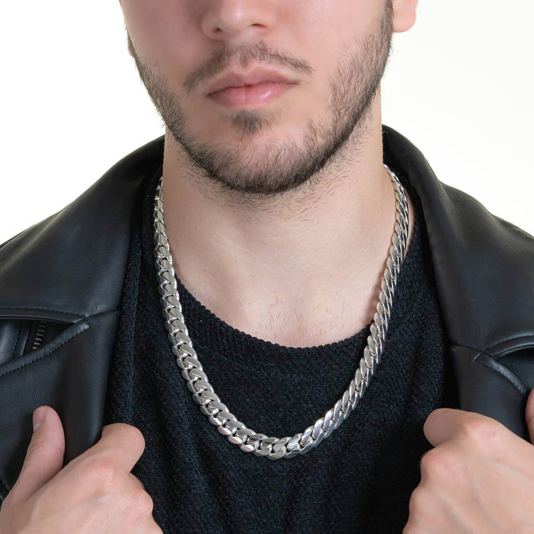 A man with a short beard wears a black shirt, black leather jacket, and a bold 12mm Handmade Miami Cuban Link Chain in 950 Silver, holding his jacket open with both hands.