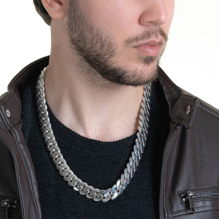 A man with a trimmed beard wears a black shirt, brown leather jacket, and a bold 16mm Handmade Miami Cuban Link Chain - 950 Silver. The photo is cropped at the nose, drawing attention to the striking necklace and upper chest.