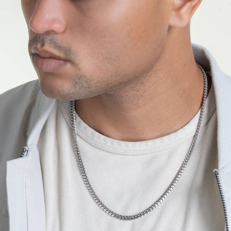 A man from the shoulders up wears a white shirt, light jacket, and the Silver Cuban Link Chain - 5mm around his neck. His lips and jawline are visible.