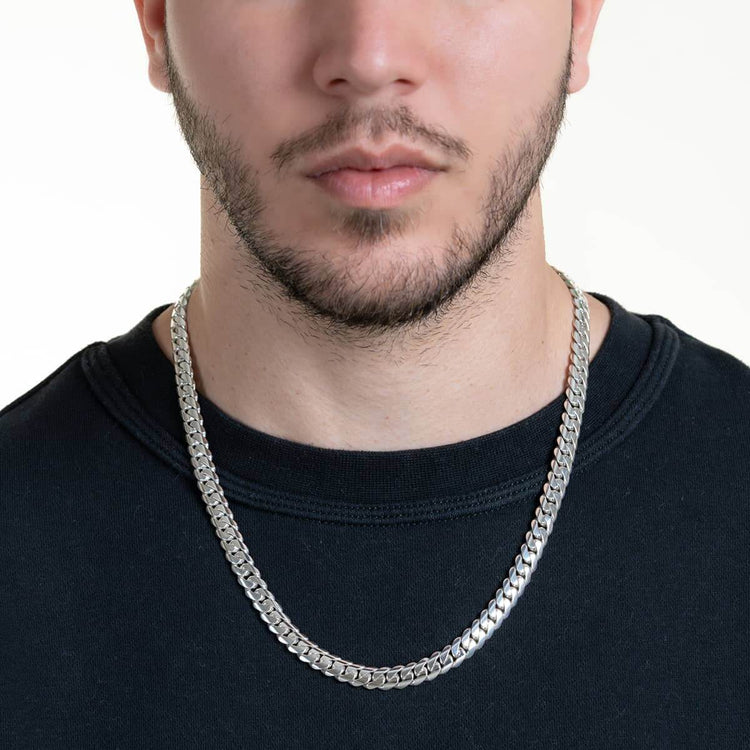 A man wearing a black crew neck shirt showcases the 8mm Handmade Miami Cuban Link Chain - 950 Silver, its thick, polished links gleaming against his neck and shoulders on a neutral white background.