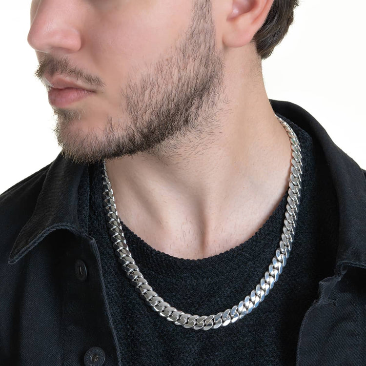 A man with a short beard, wearing a black shirt and the Handmade Miami Cuban Link Chain in 950 silver, looks to his left against a white background.