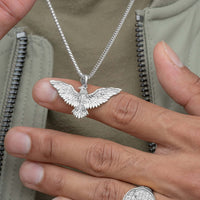 A person wearing a Silver Eagle Pendant necklace and a matching ring.