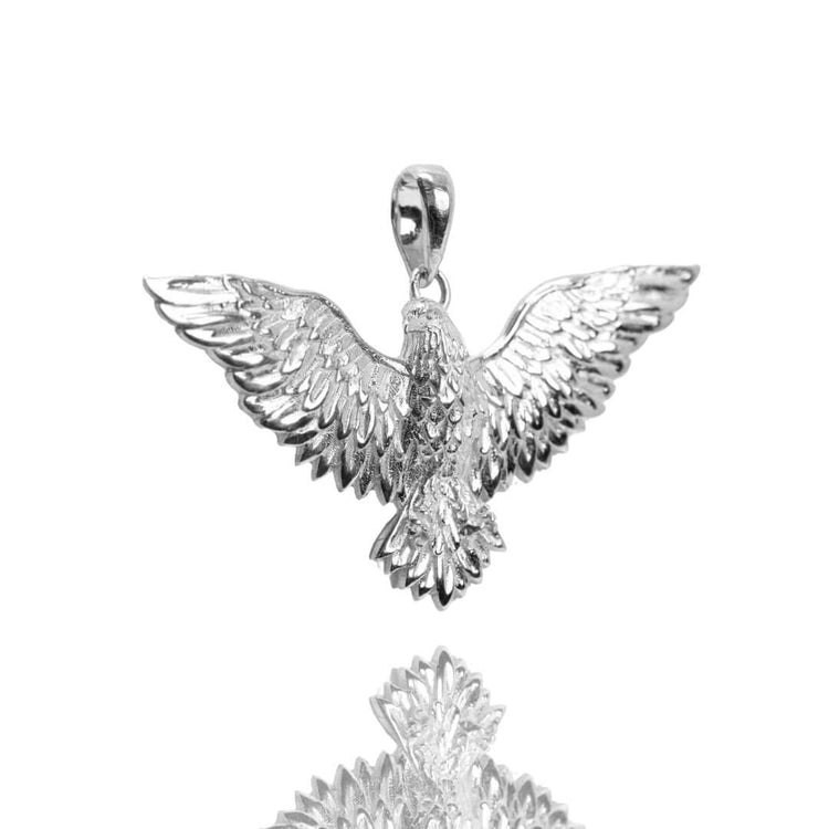 The Silver Eagle Pendant features a bold eagle with outstretched wings, crafted in solid silver and displayed on a white background with its reflection beneath.