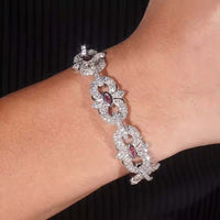 A close-up of the Eye Infinity Moissanite Bracelet, featuring sterling silver and marquise-shaped red gemstones, is showcased on a wrist against a black background.