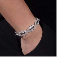 A close-up of a wrist wearing the Eye Infinity Moissanite Bracelet, a sparkling sterling silver piece with floral designs, set against a black background.