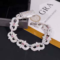 The Eye Infinity Moissanite Bracelet, featuring sparkling sterling silver with clear stones and pink marquise gems, is elegantly displayed on a black and gold surface next to a GRA certification card.