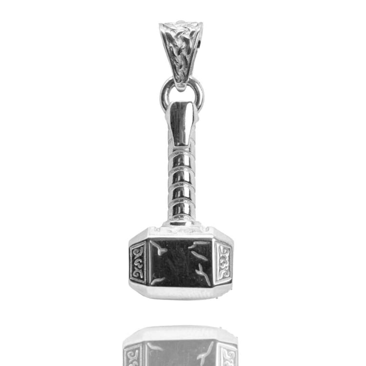 The Silver Hammer Pendant is crafted in the shape of Thor’s Mjolnir, featuring detailed engravings on the head and handle, and is displayed on a reflective white surface.