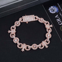 The Silver Moissanite Cross Infinity Bracelet pairs beautifully with a gold chain bracelet encrusted with small diamonds, featuring a rectangular clasp and star-shaped accents, displayed on a dark surface next to its certification card.