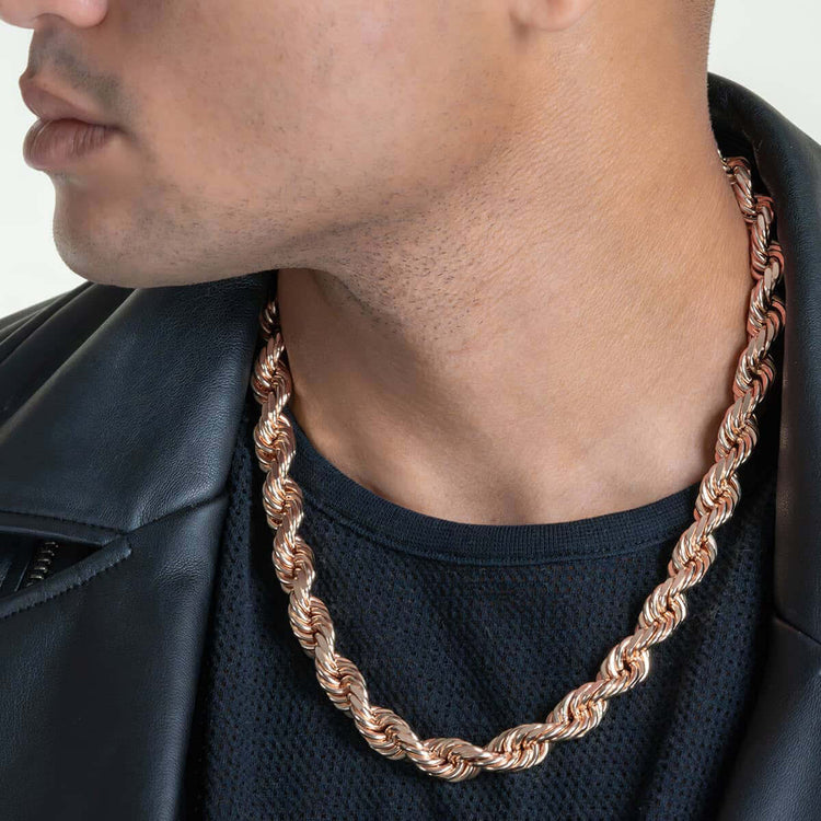 A person wearing the Rope Chain - 6mm-12mm Solid Rose Gold over a black textured shirt and leather jacket, with only the lower part of their face visible.