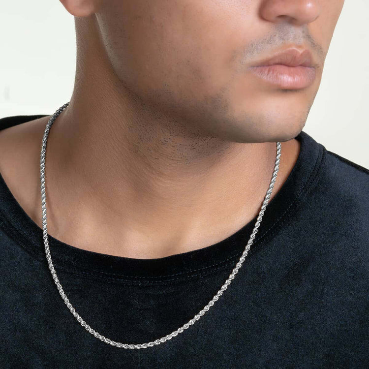 A close-up of a person wearing the Rope Chain - 2mm-5mm Solid White Gold necklace with a black shirt. The image focuses on their jawline and lips, with only part of their face visible.