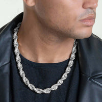 A person wears a Rope Chain - 6mm-12mm Solid White Gold necklace over a black textured shirt and black leather jacket, shown from the shoulders to just above the lips.
