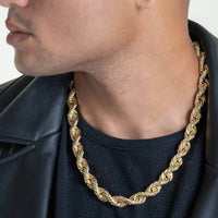 A man dressed in a black leather jacket and shirt is shown from the neck down, highlighting the Rope Chain - 6mm-15mm Solid Yellow Gold necklace—a bold, twisted statement piece around his neck.
